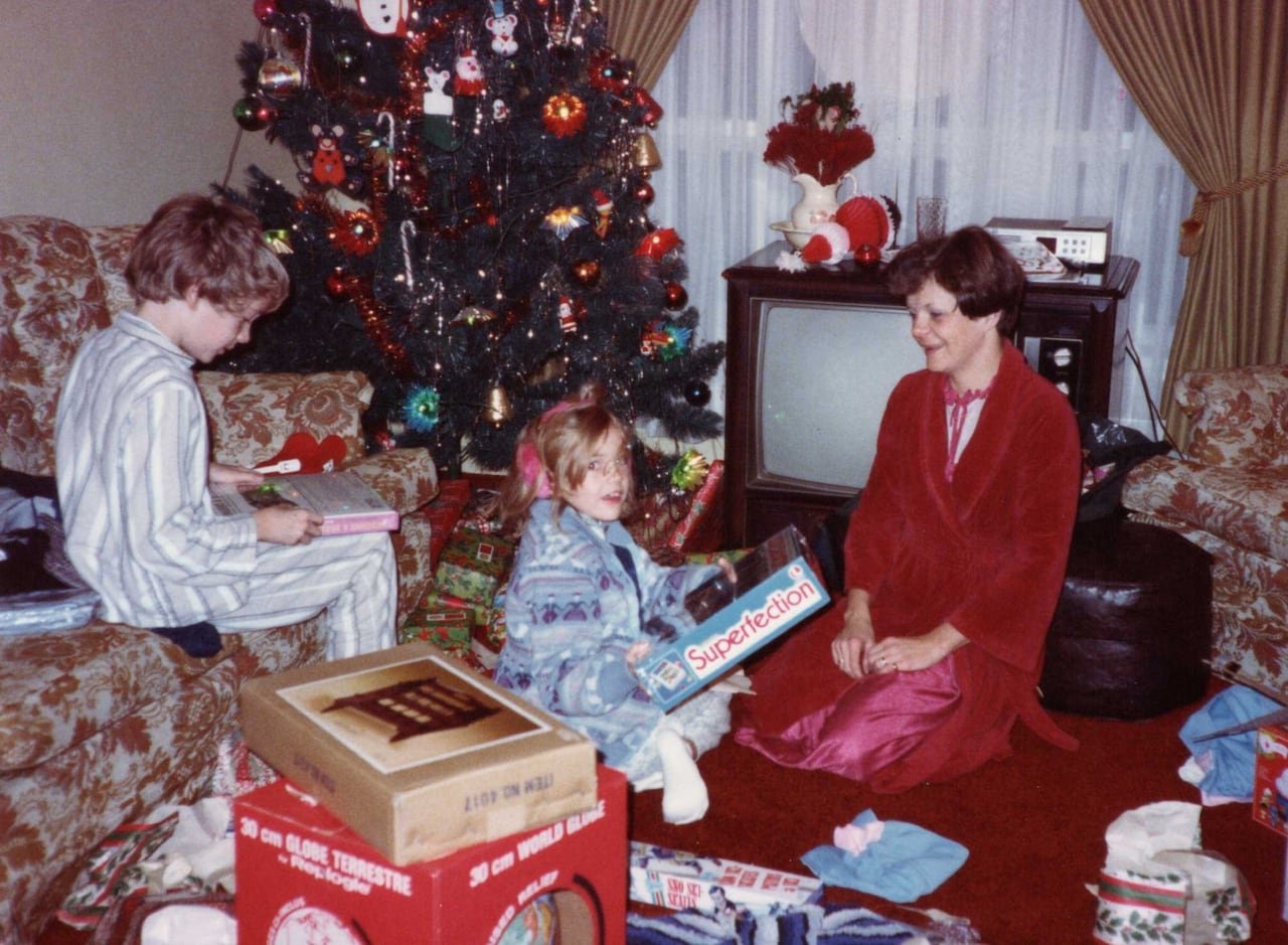 default-182 An old photograph showing a boy, a girl and their mother opening gifts on Christmas morning.
