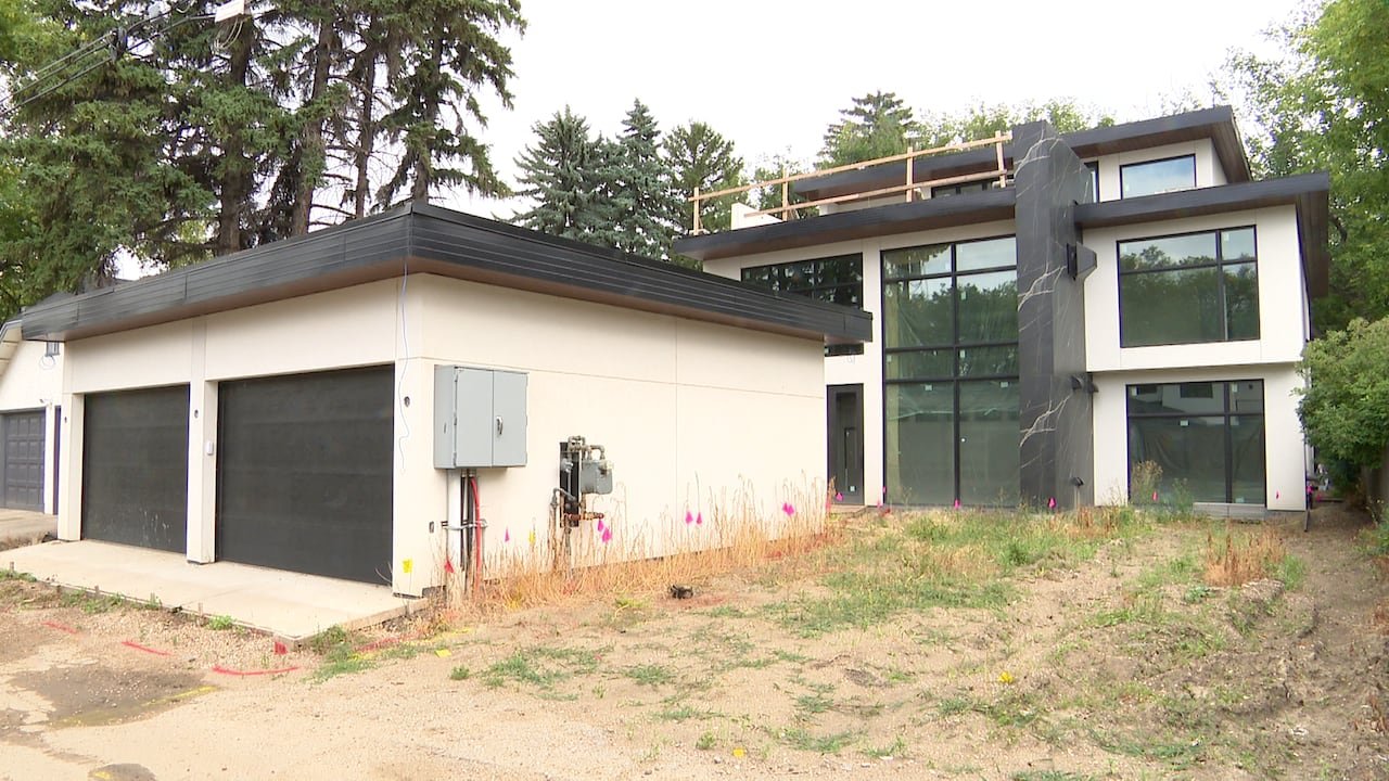 A large, flat-roofed house that's nearly finished, and a garage.